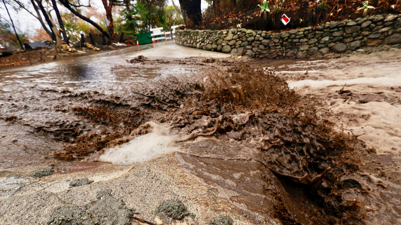 Water loaded with mud and debris churns across a wash on Rainsford Place in Zuma Canyon in an area burned by the Woolsey fire in Malibu, Calif. Thursday, Dec. 6, 2018. The second round of a fall storm is causing flooding on Los Angeles-area roads. Snow has forced the closure of Interstate 5 in the Grapevine area between LA and the San Joaquin Valley. Closer to sea level, the system dumped rain that flooded highways and caused nightmare traffic conditions for commuters. (AP Photo/Reed Saxon)