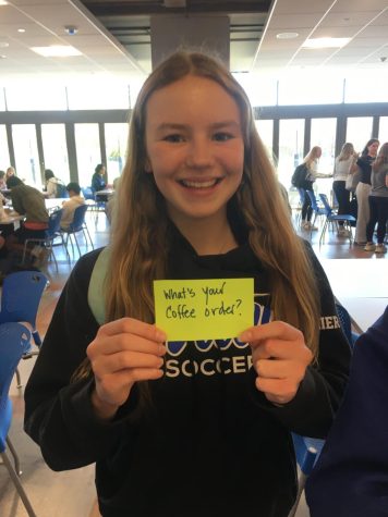 Student holding up neon index card in cafeteria
