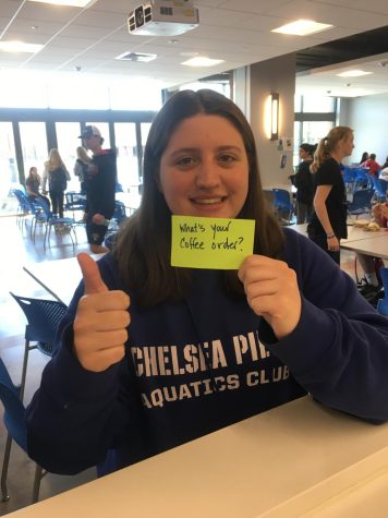 Student holding up neon index card and thumbs up in cafeteria