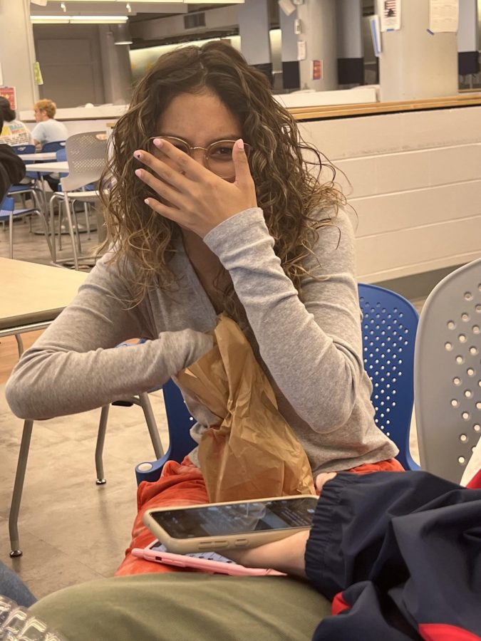 Student sitting in cafeteria with hand over face