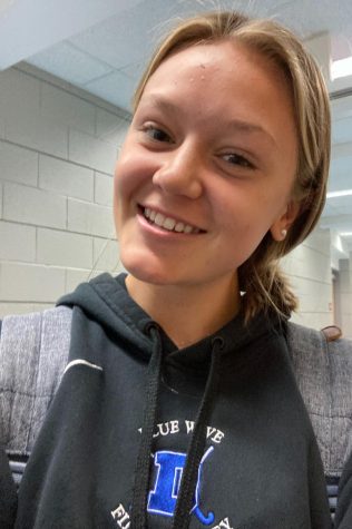 Girl smiling with a backpack in a hallway