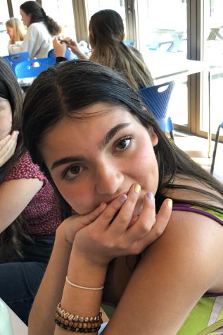 Girl sitting down with her hands covering her mouth