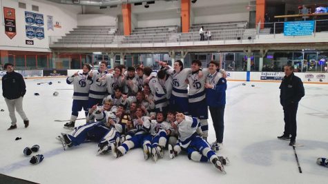 The Darien Varsity Boys Ice Hockey team celebrating with the FCIAC trophy inside the Danbury Ice Arena