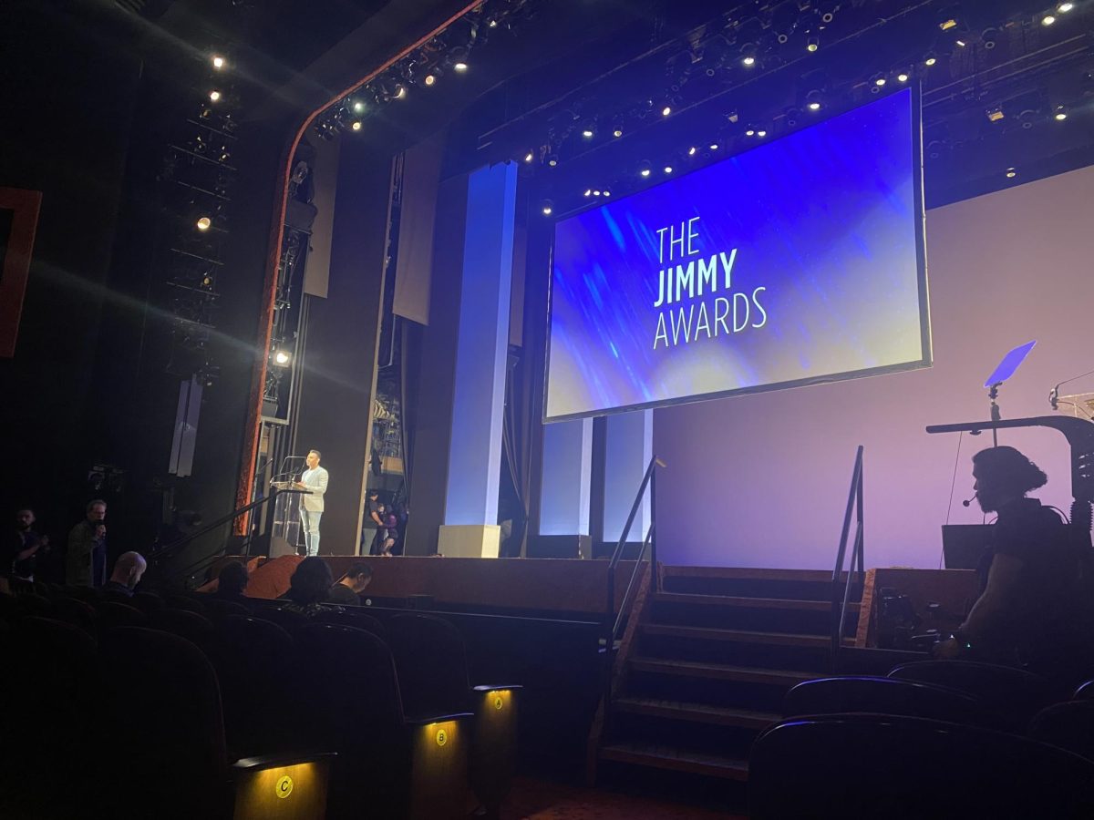 The Minskoff stage is illuminated by the glowing Jimmy Awards projection. Corbin Bleu, the host of the evening, rehearses his lines one final time.