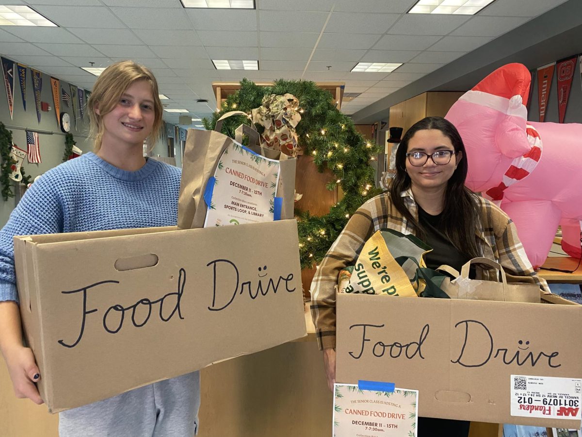 Senior Class Representative Amanda Smith and Kiara Luciano holding the collected food items that will be donated to Person 2 Person.