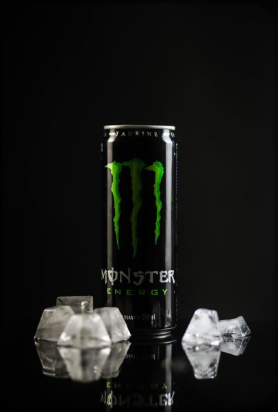 A can of the "Monster" energy drink with four ice cubes on the left of the can and two ice cubes on the right of the can.